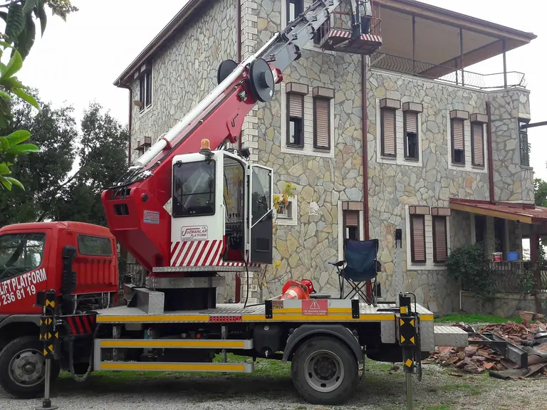 Taş bina önünde araç üstü sepetli vinç